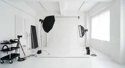 清潔感あふれる白い撮影スタジオ：プロ用機材とシームレス背景。白とグレーを基調とした清潔感あふれるプロ仕様の撮影スタジオの全景で、ストロボ、ソフトボックス、三脚などの豊富な機材が完備されています。