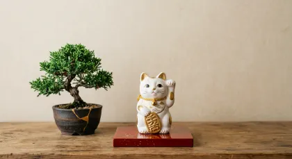 金色の招き猫とミニ盆栽が彩る和風インテリア。金色のアクセントが施された招き猫と、趣のあるミニ盆栽が並べられた、穏やかな和風空間の画像です。